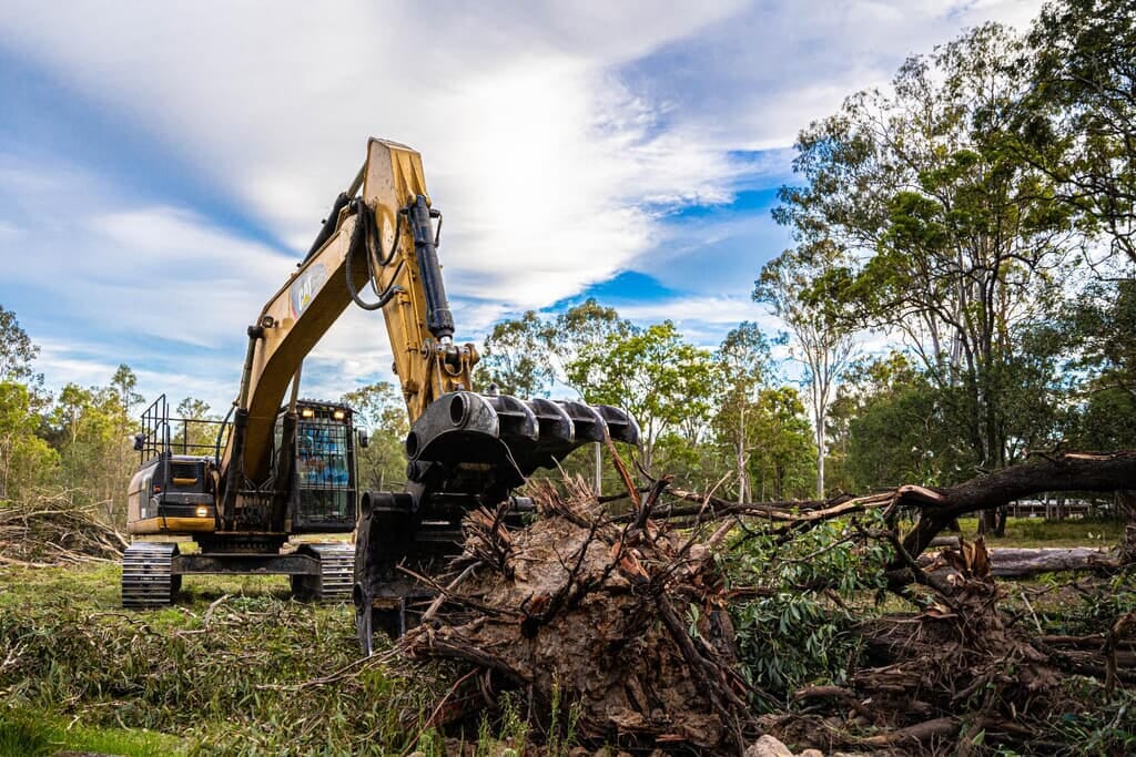 Excavator clearing a fallen tree and root ball