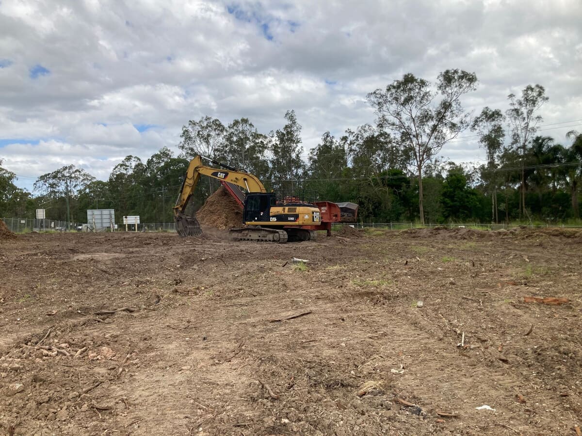 Excavator feeding the HOG 3800 grinder on the cleared Old Pub Lane site