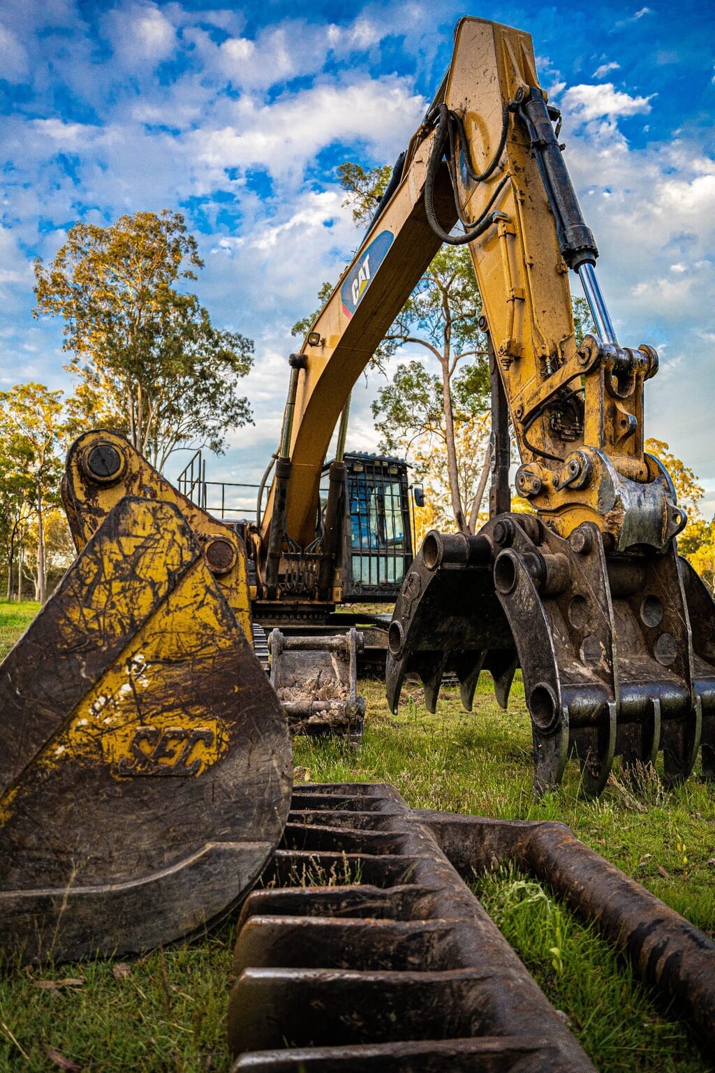 Tree Eaters excavator with bucket, grapple and stick rake attachments lined up on site